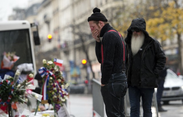 Singer of the US rock group Eagles of Death metal Jesse Hughes (L) and guitarist Dave Catching pay tribute to the victims of the November 13 Paris terrorist attacks at a makeshift memorial in front of the Bataclan concert hall on December 8, 2015 in Paris. The Eagles of Death Metal band returned to the Bataclan concert hall in Paris, nearly a month after they survived a jihadist attack there in which 90 people died. / AFP / MIGUEL MEDINA