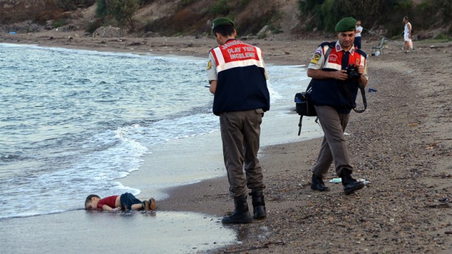 ADDS IDENTIFICATION OF CHILD Paramilitary police officers investigate the scene before carrying the lifeless body of Aylan Kurdi, 3, after a number of migrants died and a smaller number were reported missing after boats carrying them to the Greek island of Kos capsized, near the Turkish resort of Bodrum early Wednesday, Sept. 2, 2015. The family — Abdullah, his wife Rehan and their two boys, 3-year-old Aylan and 5-year-old Galip — embarked on the perilous boat journey only after their bid to move to Canada was rejected. The tides also washed up the bodies of Rehan and Galip on Turkey's Bodrum peninsula Wednesday, Abdullah survived the tragedy. AP