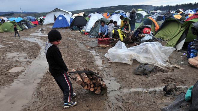 A boy carries wood on March 10, 2016 at the Greek-Macedonian border near the Greek village of Idomeni where thousands of refugees and migrants are trapped by the Balkan border blockade. The German and Greek leaders blasted Balkan countries for shutting their borders to migrants ahead of an EU ministers meeting on March 10. Greek authorities said there were 41,973 asylum seekers in the country, including some 12,000 stuck at Idomeni on the closed Macedonian border. / AFP / SAKIS MITROLIDIS