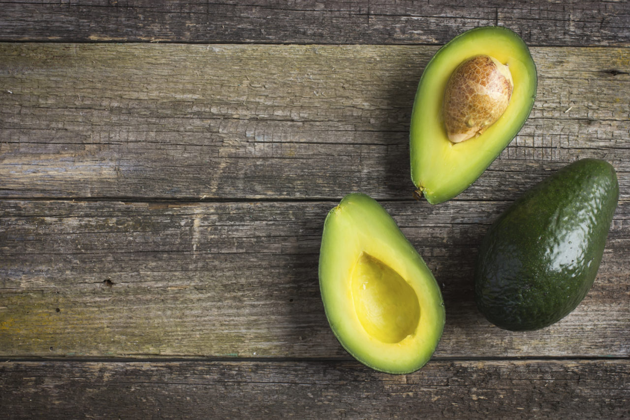 food background with fresh organic avocado on old wooden table, top view, copy space